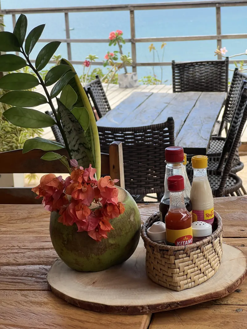Mesa arrumada com coco e temperos de frente para o mar