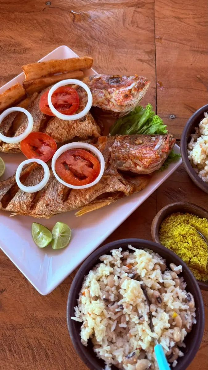 Dois peixes fritos inteiros com macaxeira, tomate e cebola, arroz baião e farofa